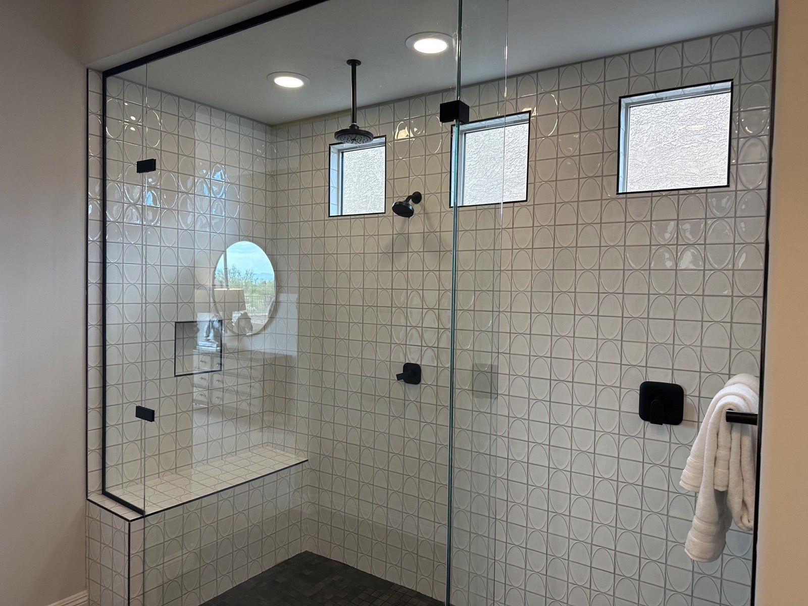 Corner walk-in shower with large-format tile, mosaic accents, bench, and black fixtures