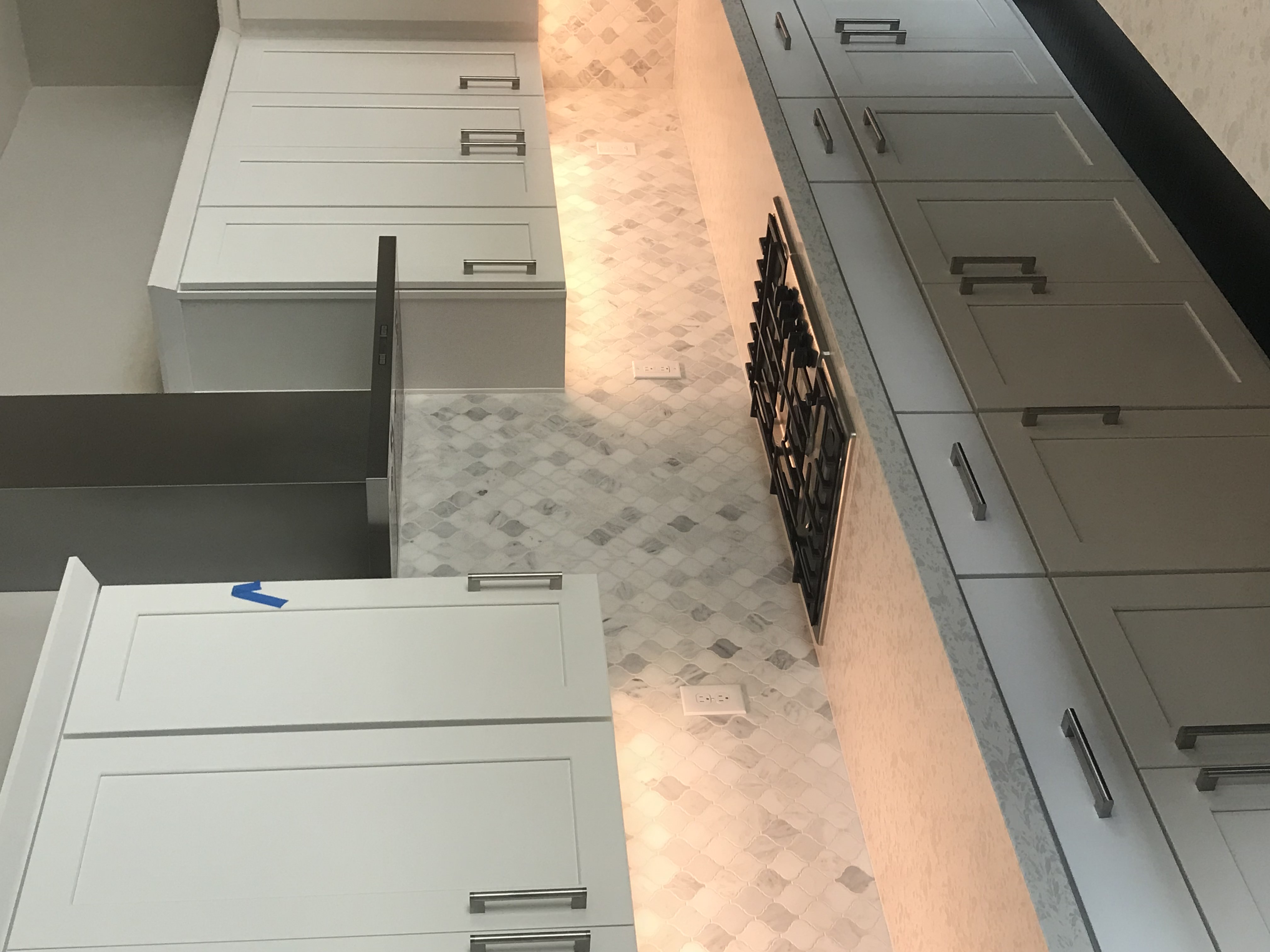 White and gray cabinets with marble-pattern arabesque tile backsplash and gas cooktop