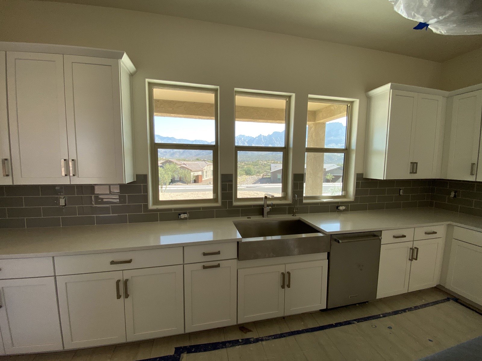 Light gray kitchen cabinets with glass uppers, white countertops, and mosaic tile backsplash