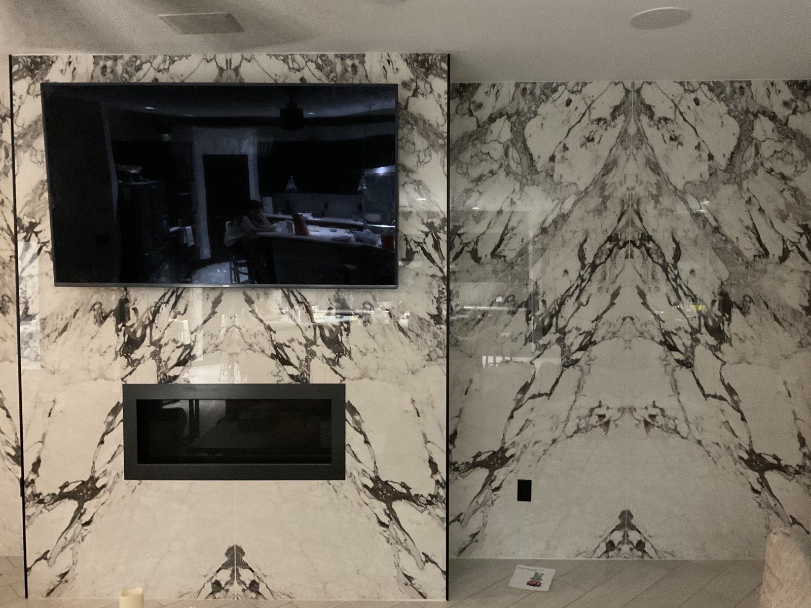 Book-matched marble feature wall with built-in fireplace and wall-mounted television